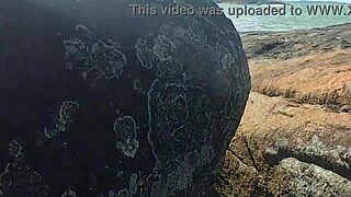 Young beauty watched having public sex on beach rocks