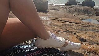 Young beauty watched having public sex on beach rocks