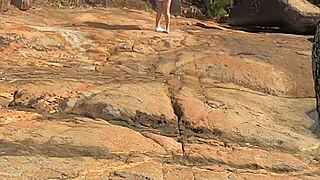 Young beauty watched having public sex on beach rocks