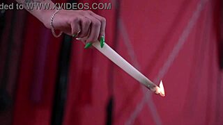 Pouring hot wax on slave's slender legs in latex domination session