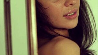 dark haired young beauty undresses sensually touching shaved body in mirror